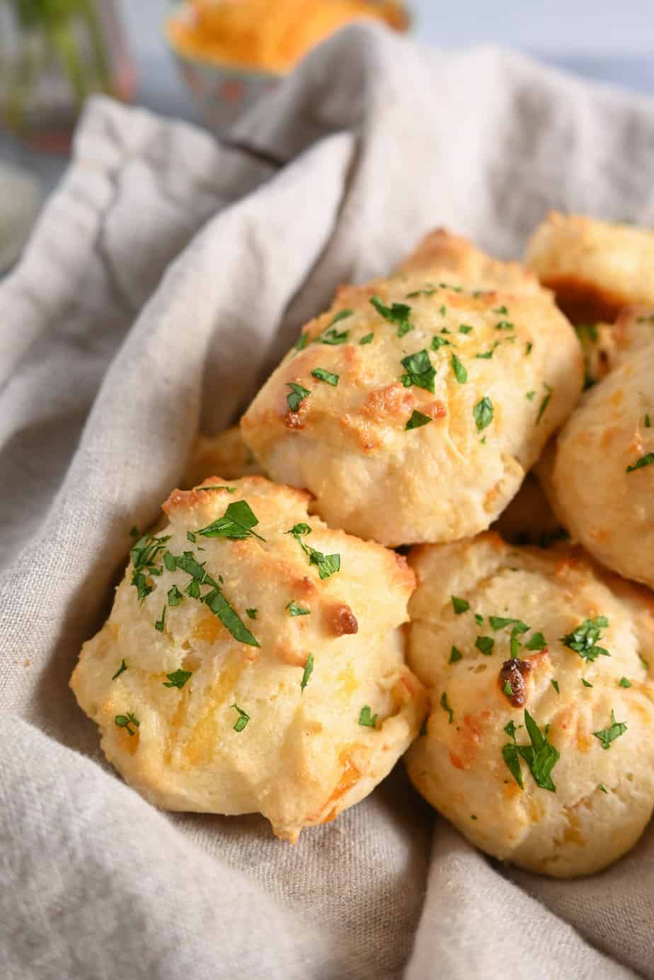Close up of parsley-topped red lobster biscuits in a basket lined with a linen napkin.