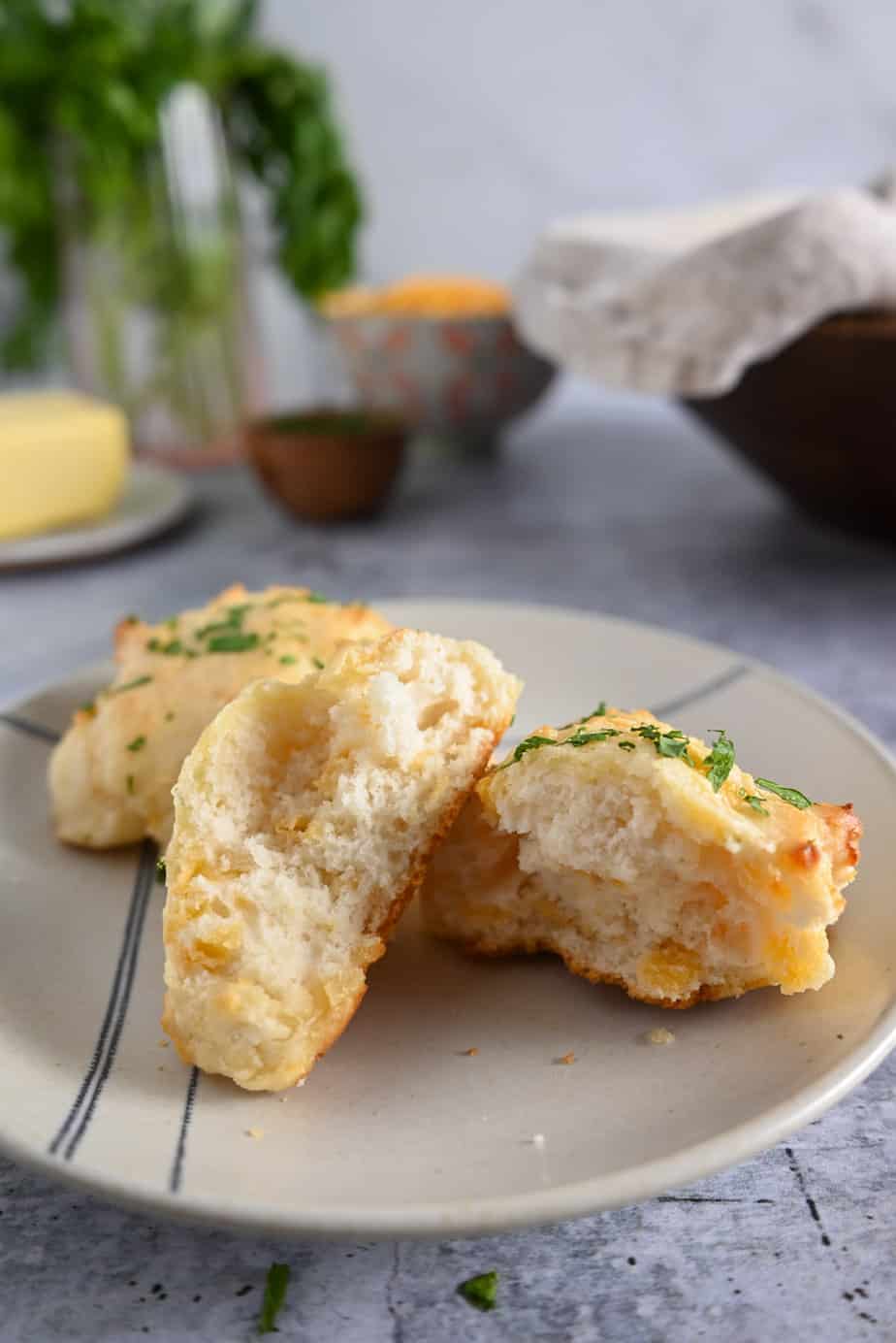 Two homemade red lobster biscuits on a plate. One of the biscuits is broken in half to show the fluffy inner texture.