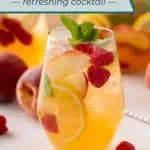 Side view of a glass filled with white peach sangria and garnished with fresh mint. Text overlay includes recipe name.