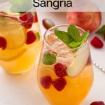 Two glasses filled with white peach sangria and garnished with fresh mint. Text overlay includes recipe name.