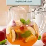 Side view of a glass pitcher filled with white peach sangria and garnished with sprigs of mint. Text overlay includes recipe name.