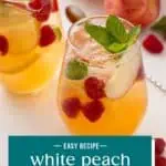 Side view of a glass pitcher filled with white peach sangria and garnished with sprigs of mint. Text overlay includes recipe name.