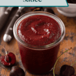 Jar of cherry barbecue sauce set on a wooden board. Text overlay includes recipe name.