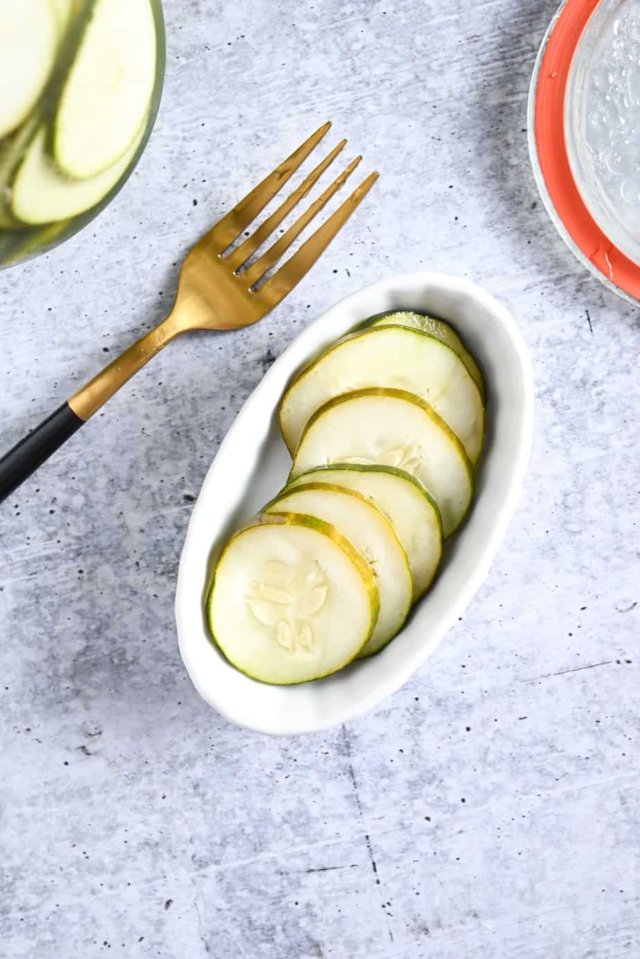 Overhead view of a white oval dish filled with pickled cucumbers.