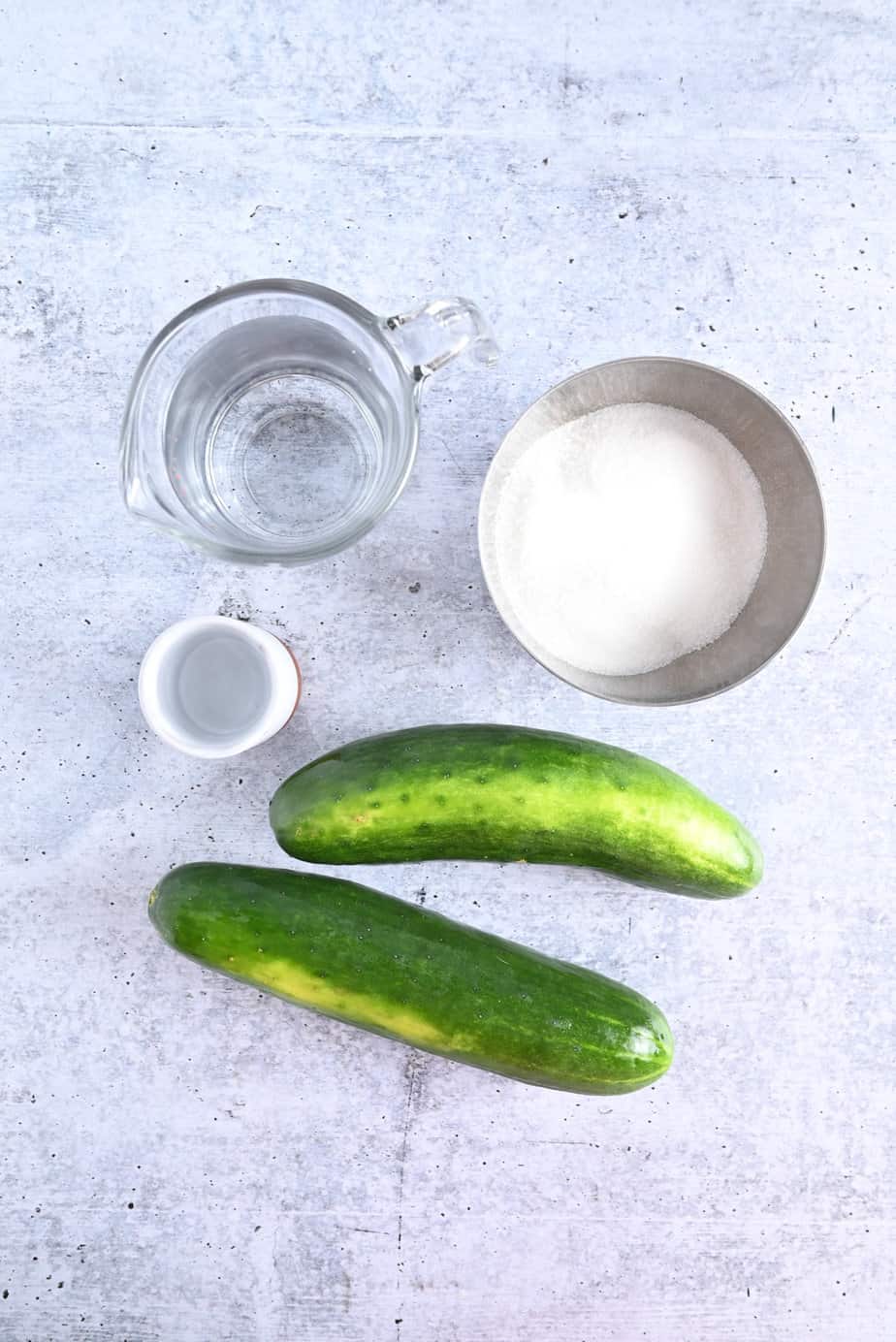 Ingredients for pickled cucumbers arranged on a concrete countertop.