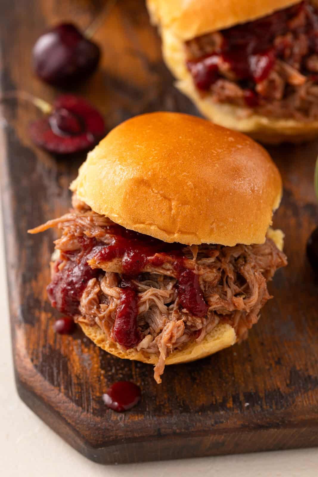 Cherry barbecue sauce drizzled over pulled pork on bun.