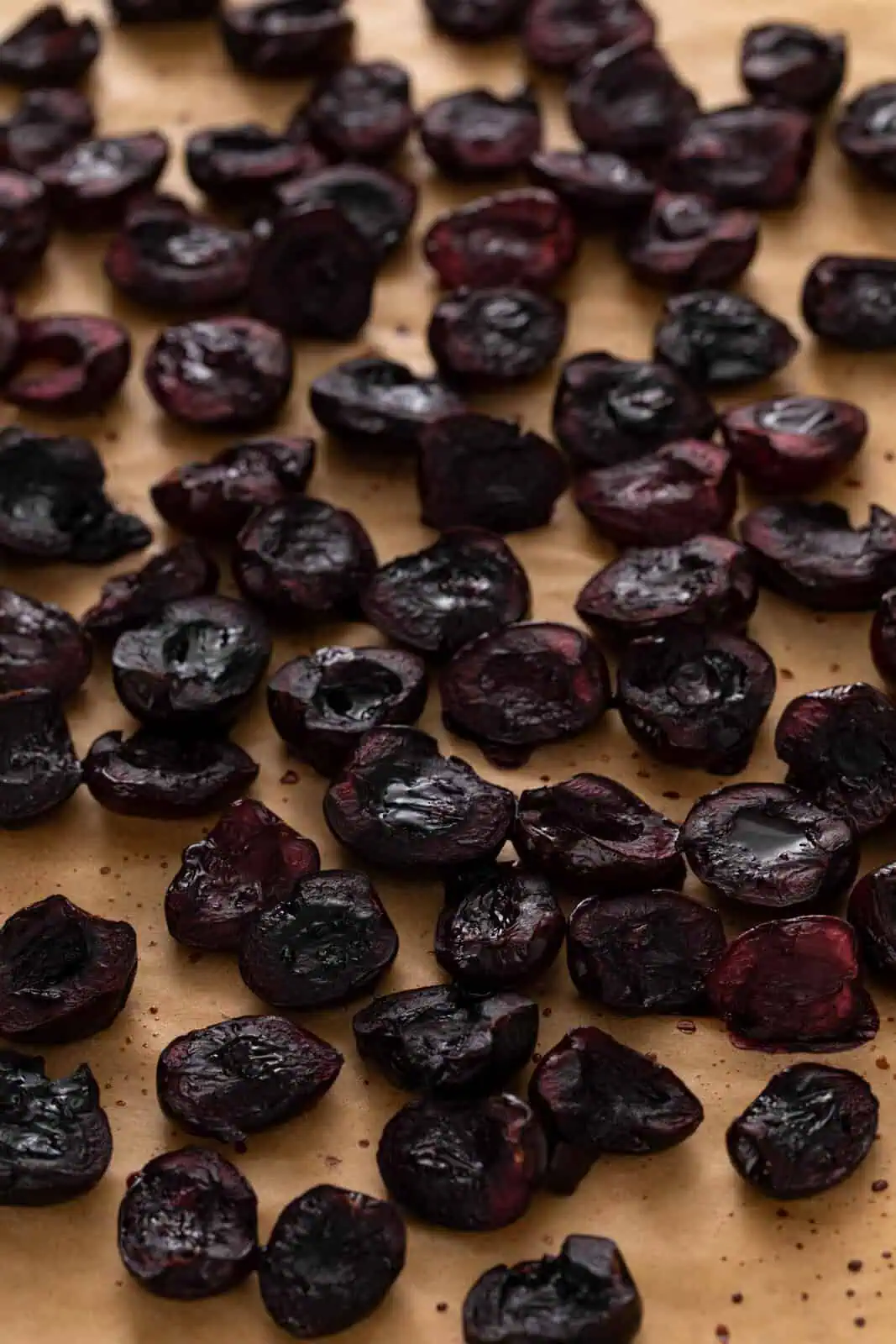 Close up of roasted sweet cherries on a parchment-lined pan.