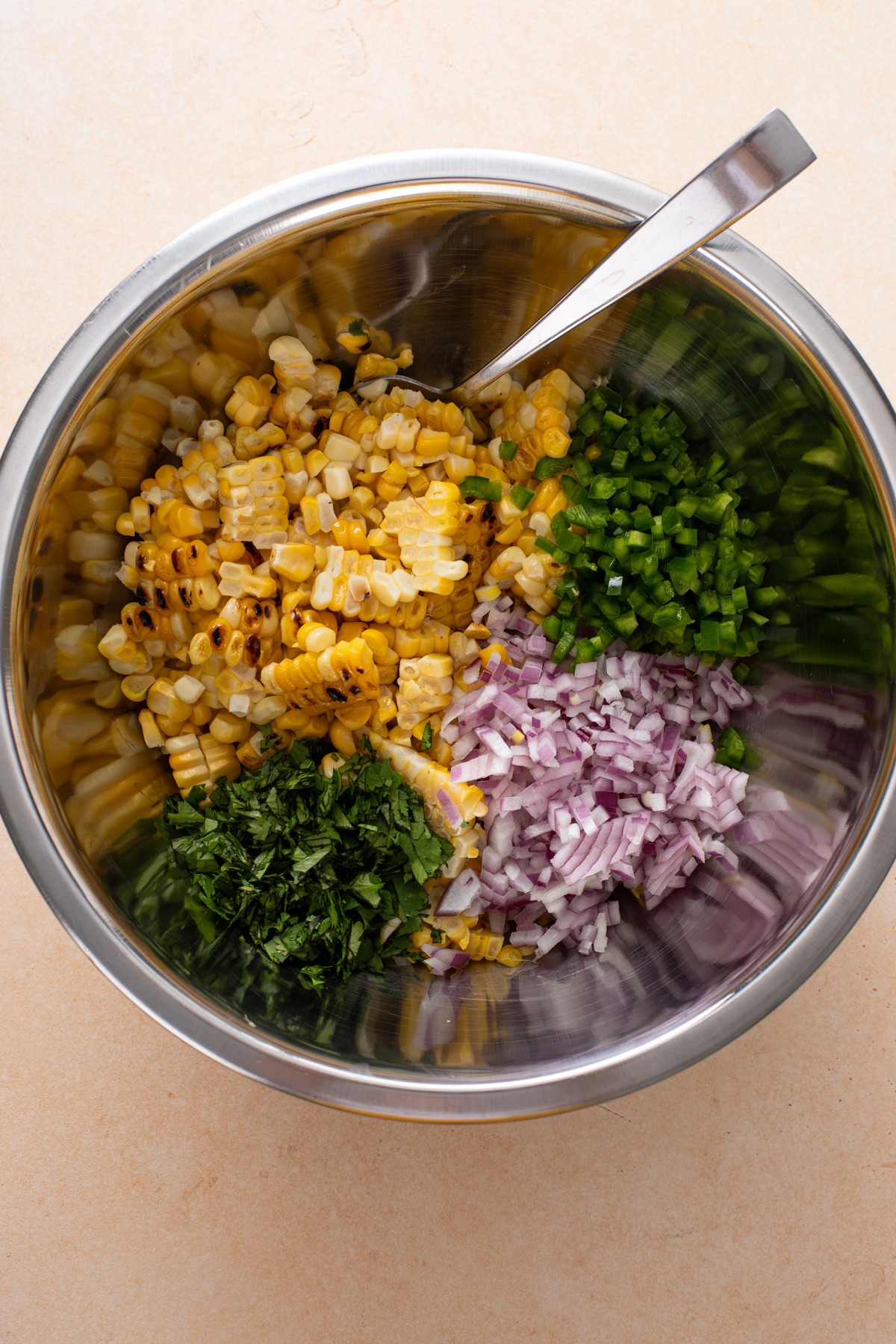 Ingredients for roasted corn salsa added to a metal mixing bowl.