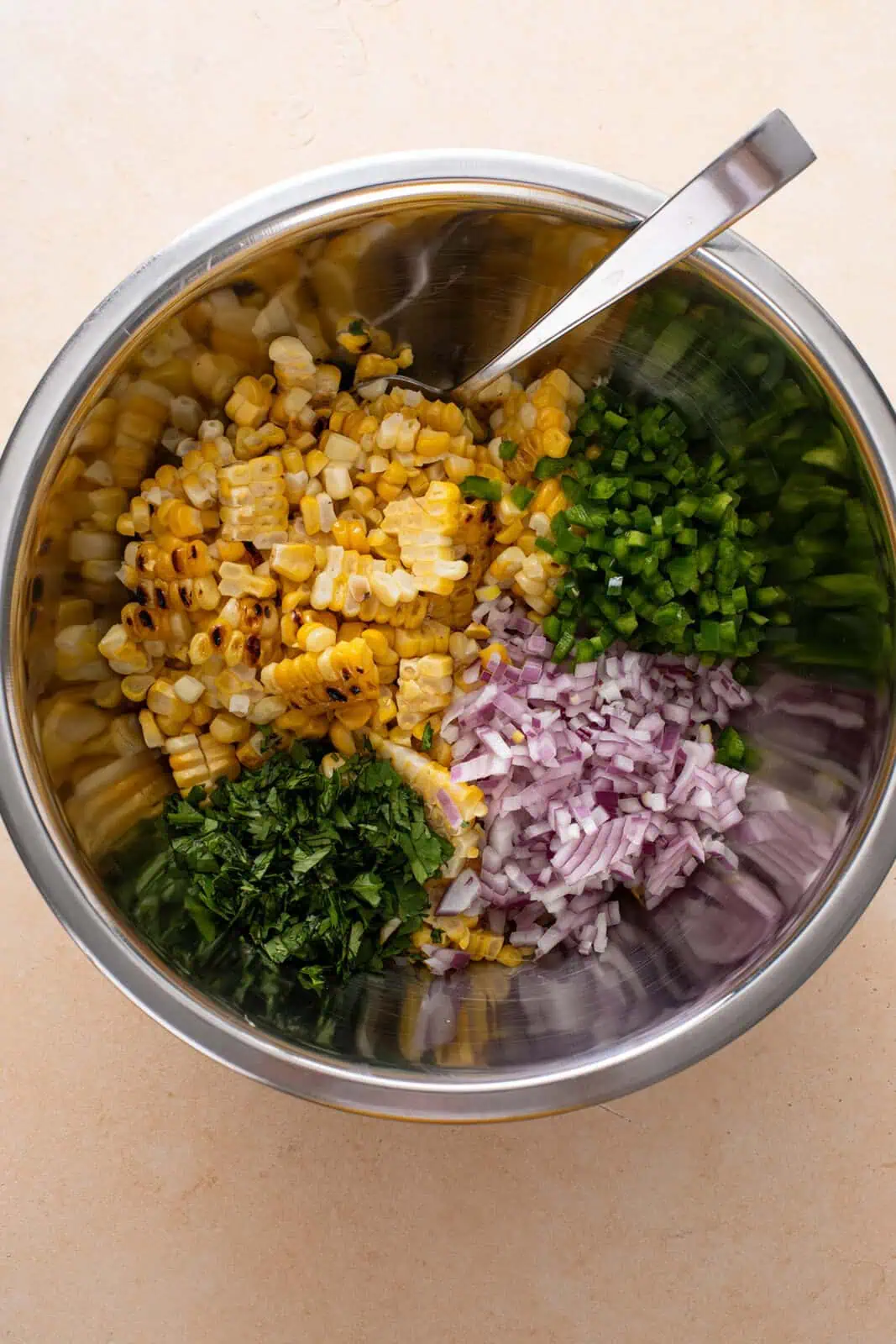Ingredients for roasted corn salsa added to a metal mixing bowl.