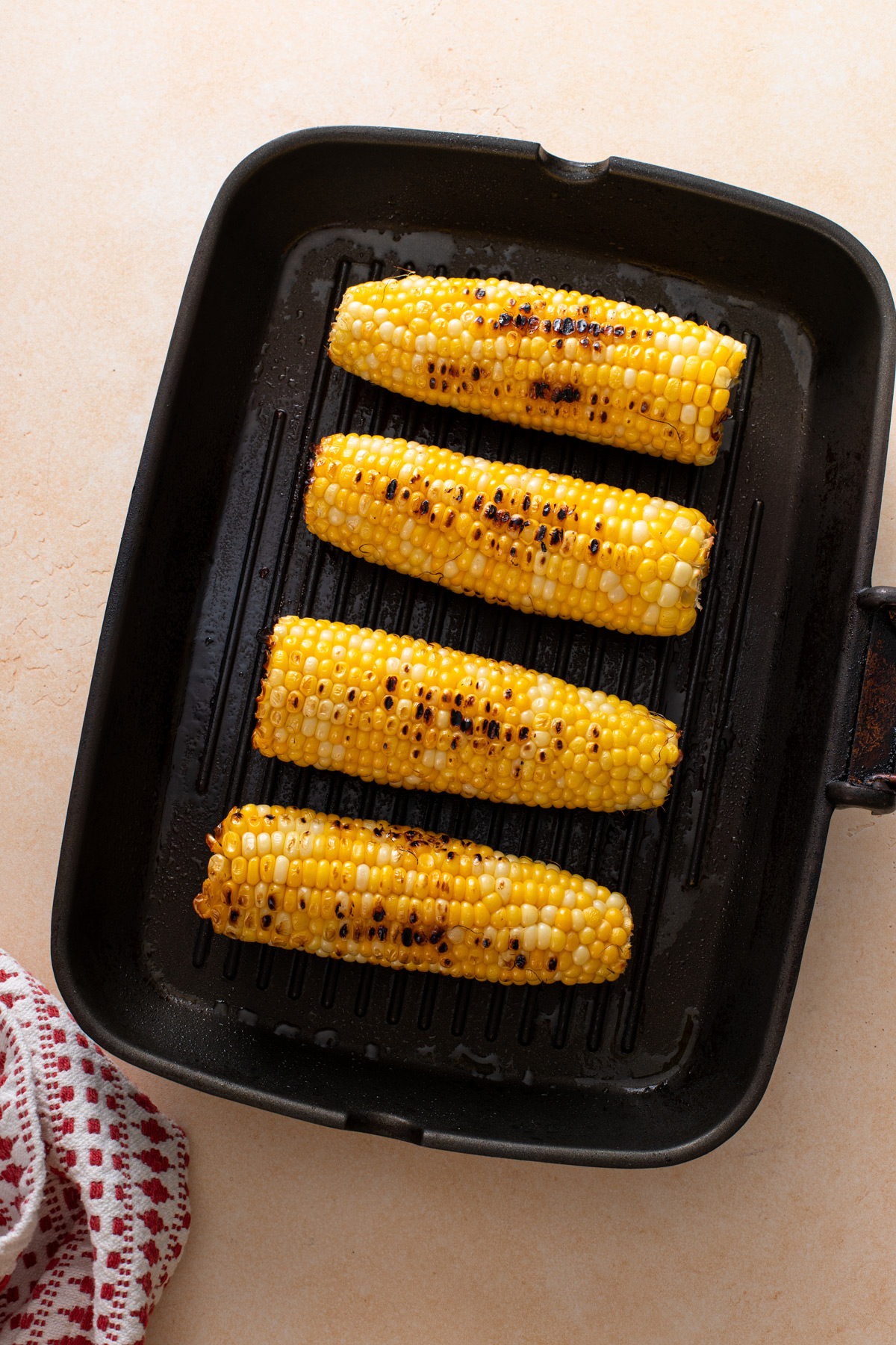 Four ears of roasted sweet corn on a grill pan.