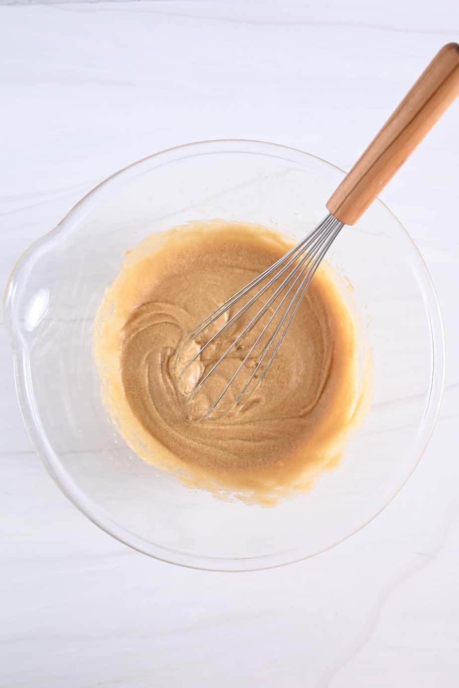 Wet ingredients for maple walnut blondies being whisked together in a glass mixing bowl.