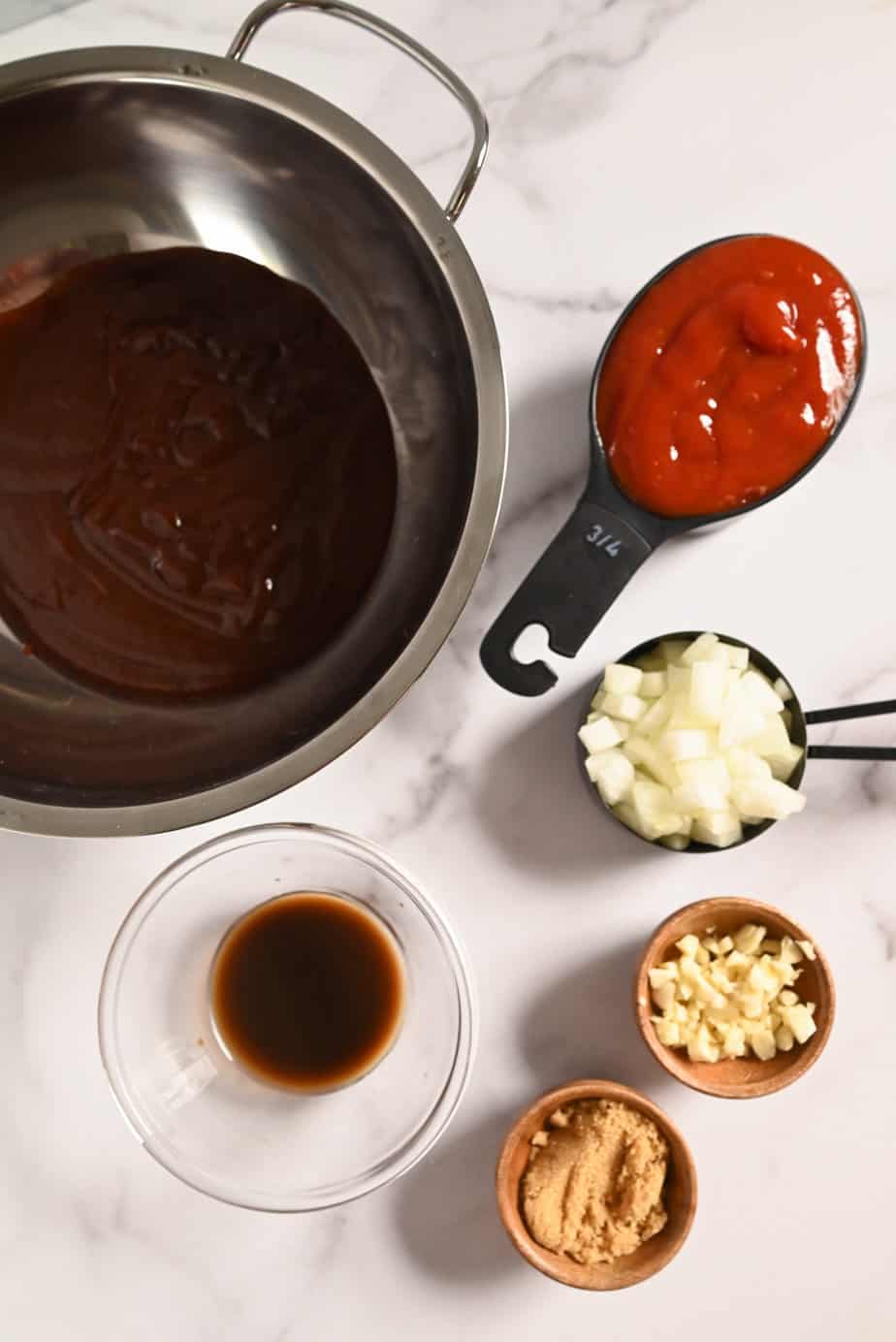Ingredients for crockpot pulled chicken sauce arranged on a marble countertop.