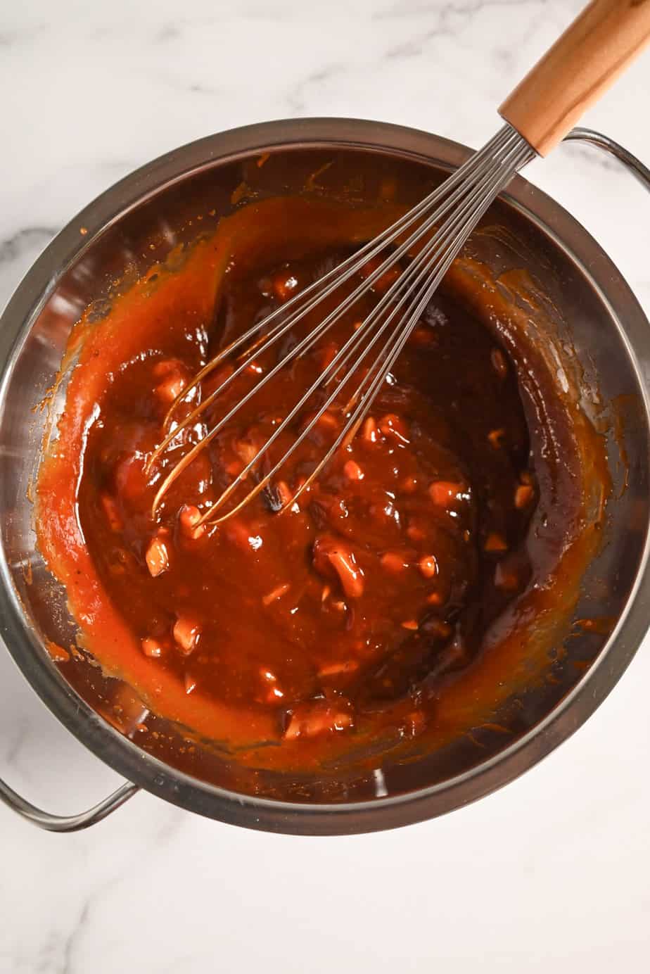 Sauce for crockpot pulled chicken being whisked together in a metal bowl.
