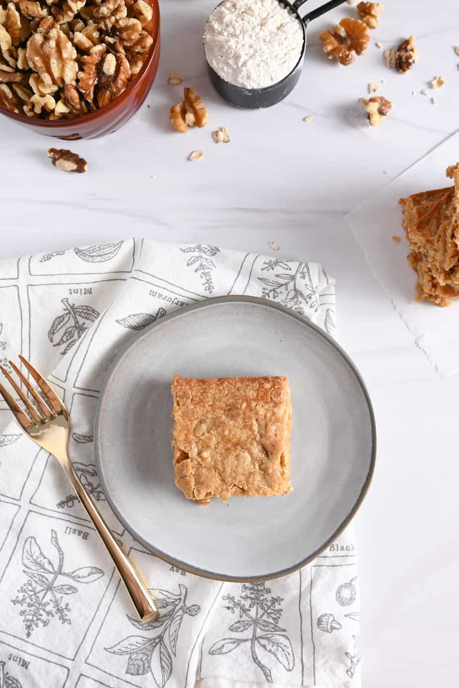 Overhead view of a maple walnut blondie on a small gray plate.