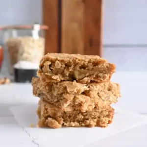 Three maple walnut blondies stacked on a piece of parchment paper.