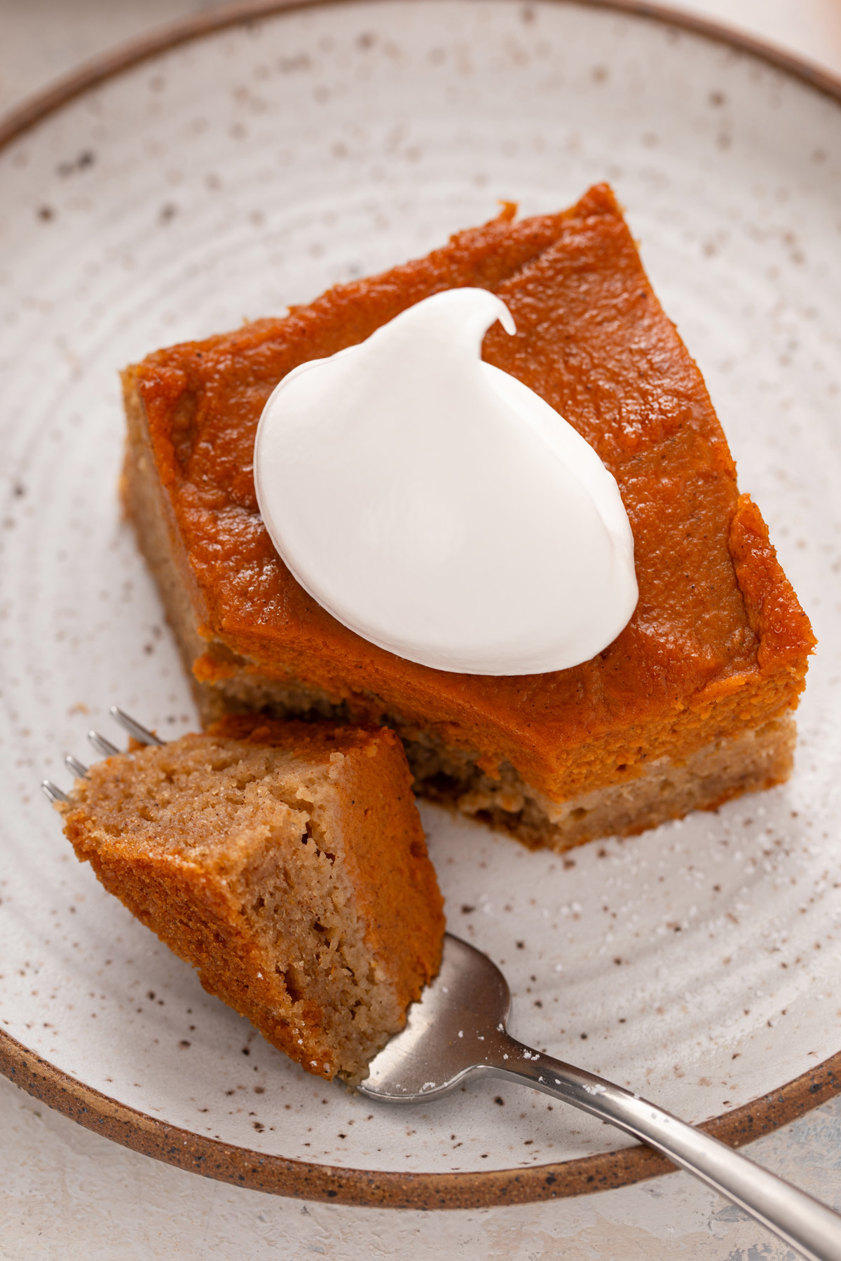 Fork cutting a bite from the corner of a slice of pumpkin spice cake.