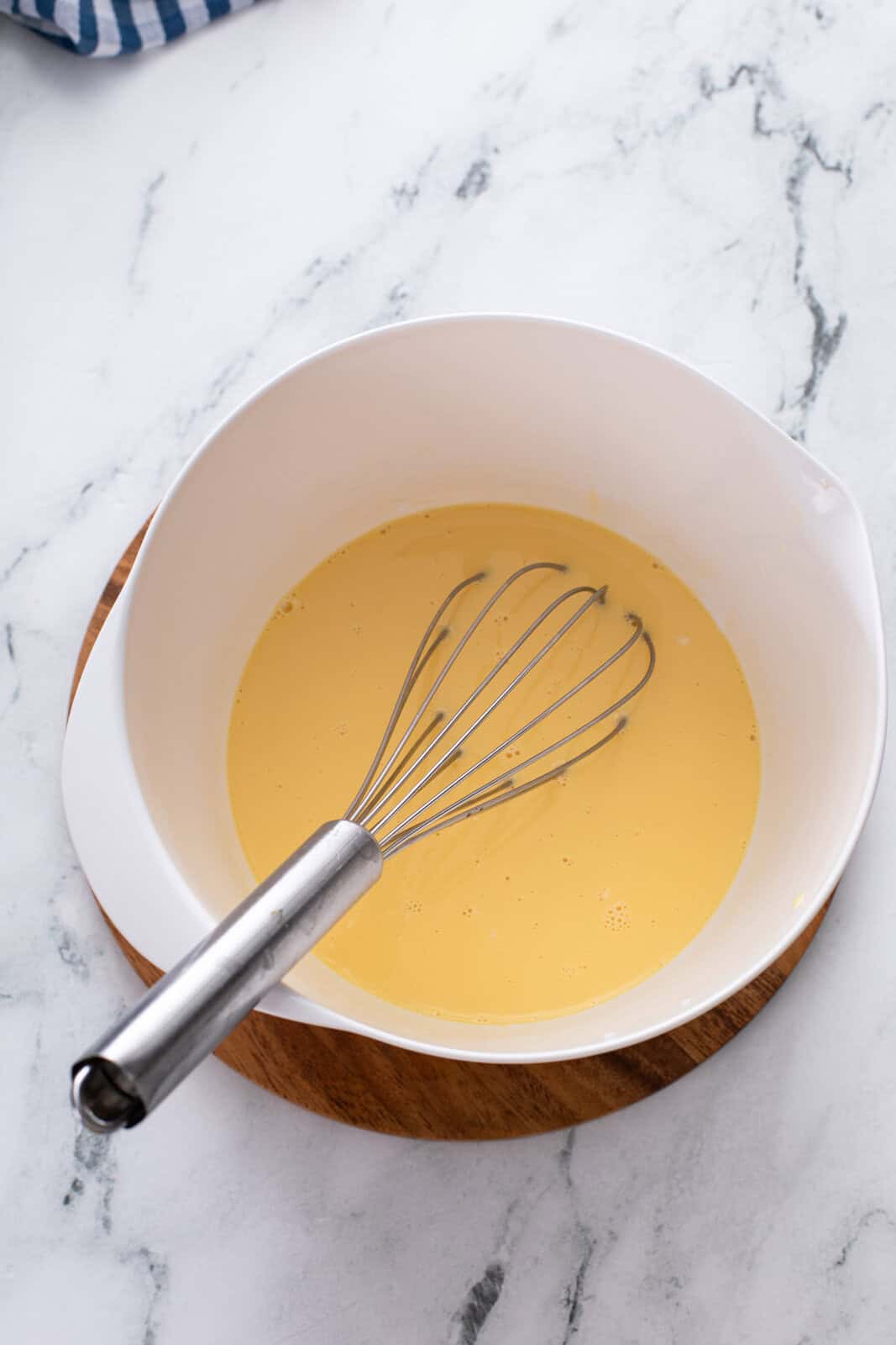 Egg yolks and evaporated milk whisked in a bowl.