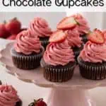 Chocolate cupcakes topped with strawberry frosting arranged on a pink cake stand. Text overlay includes recipe name.