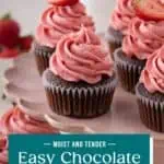 Close up of easy chocolate cupcakes topped with strawberry frosting on a pink cake stand. Text overlay includes recipe name.