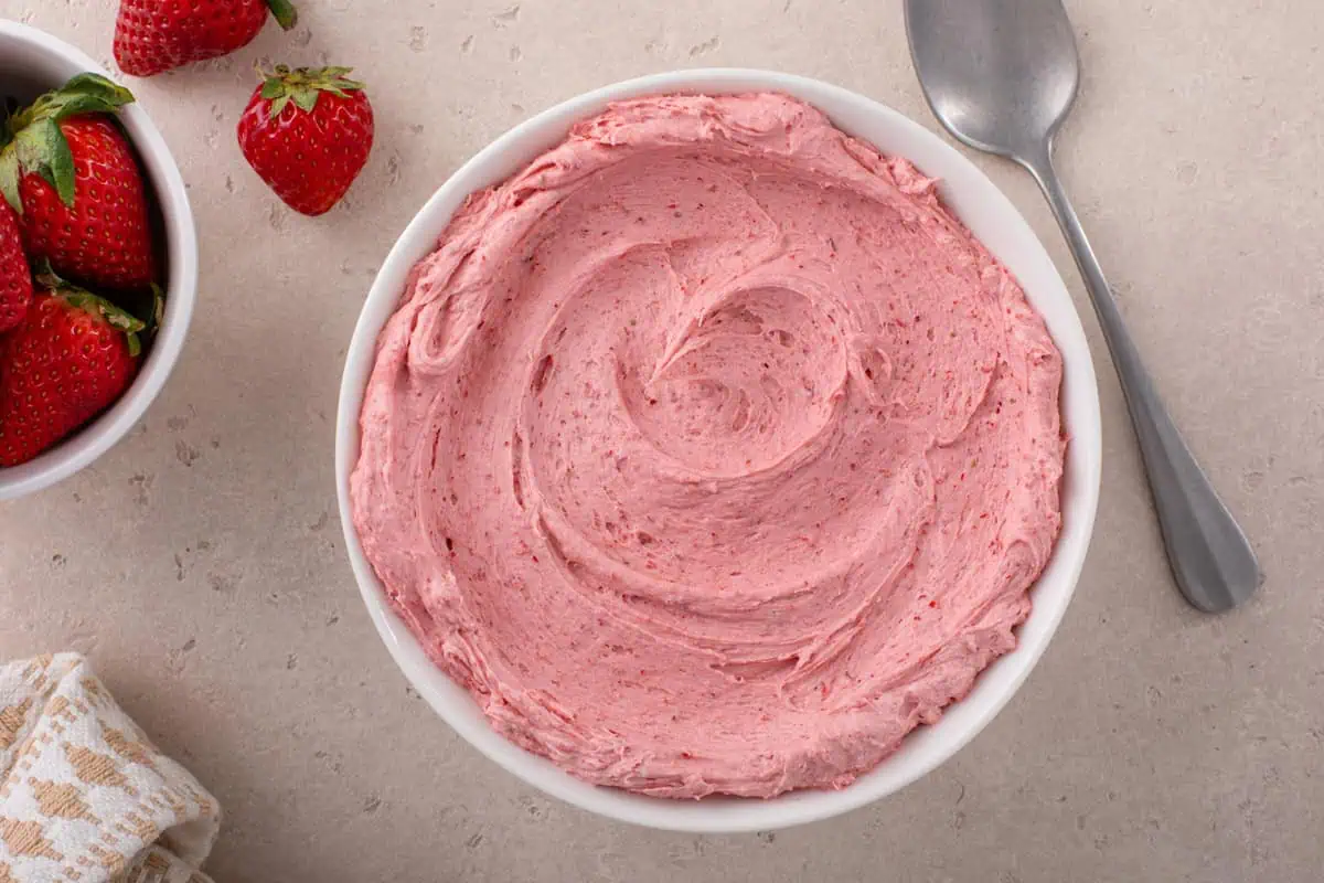 Overhead view of strawberry buttercream in a white bowl.