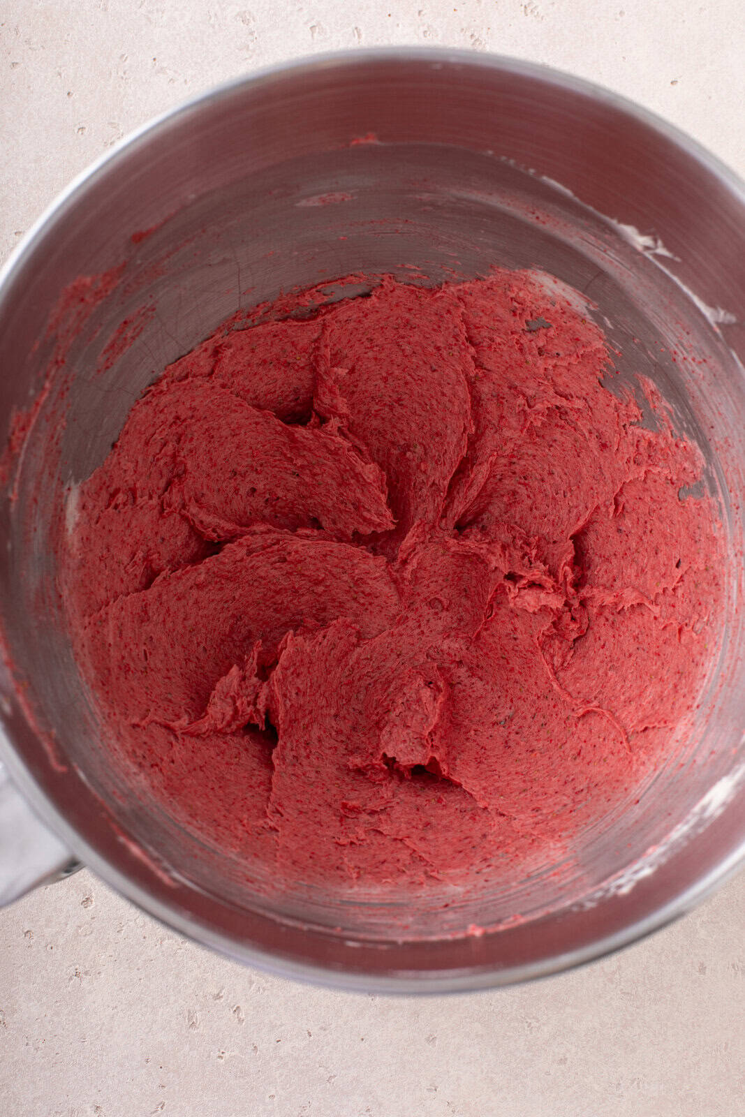 Crushed freeze-dried strawberries and butter mixed in the bowl of a stand mixer.
