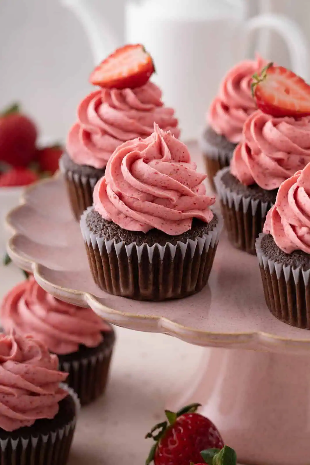 Close up of easy chocolate cupcakes topped with strawberry frosting on a pink cake stand.