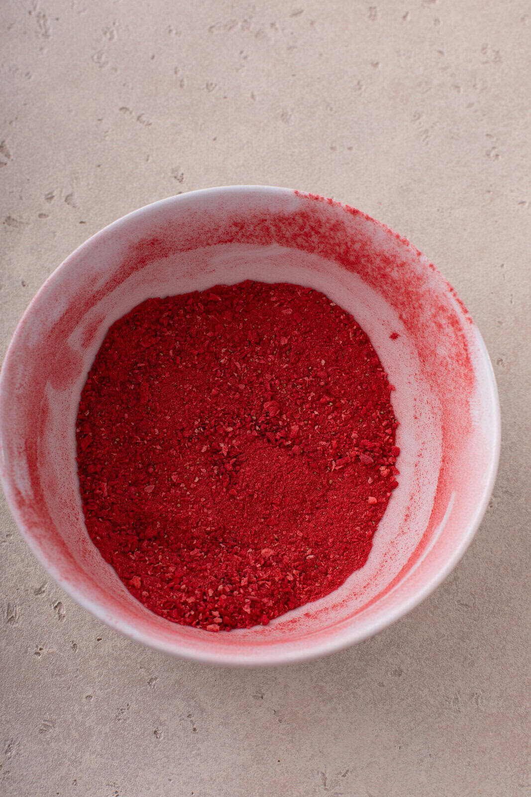 Crushed freeze-dried strawberry powder in a white bowl.