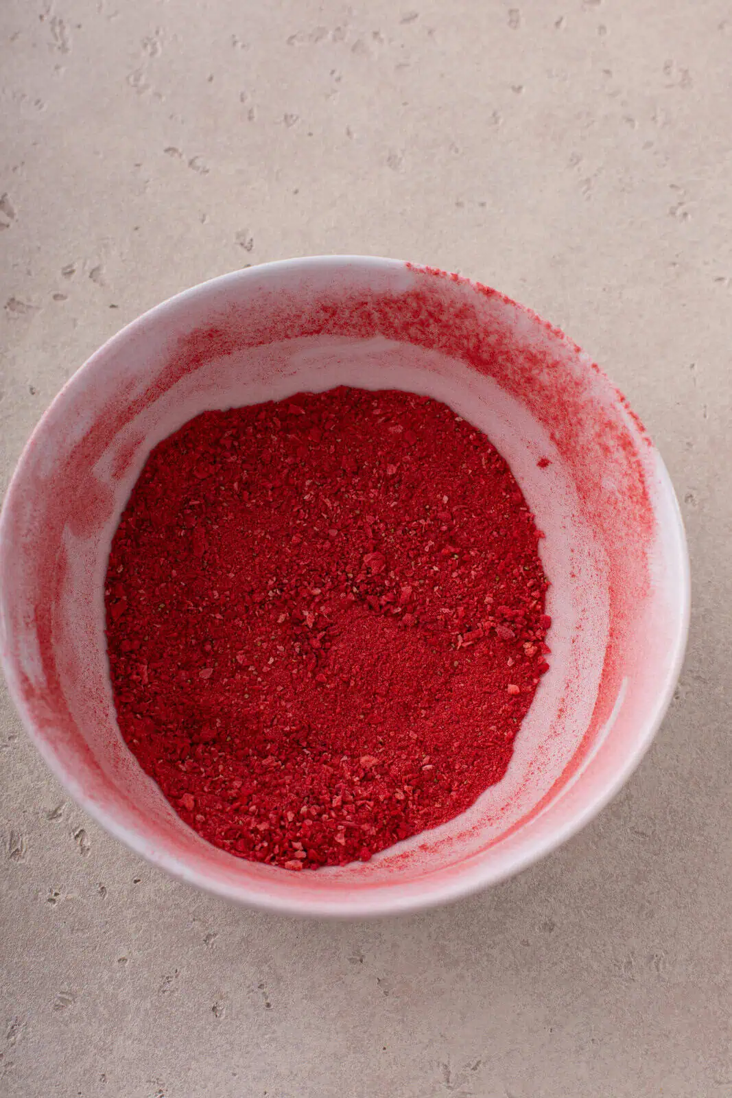 Crushed freeze-dried strawberry powder in a white bowl.