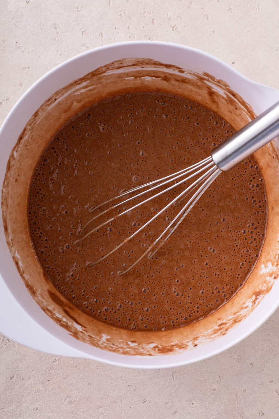 Cake batter for easy chocolate cupcakes whisked in a white mixing bowl.