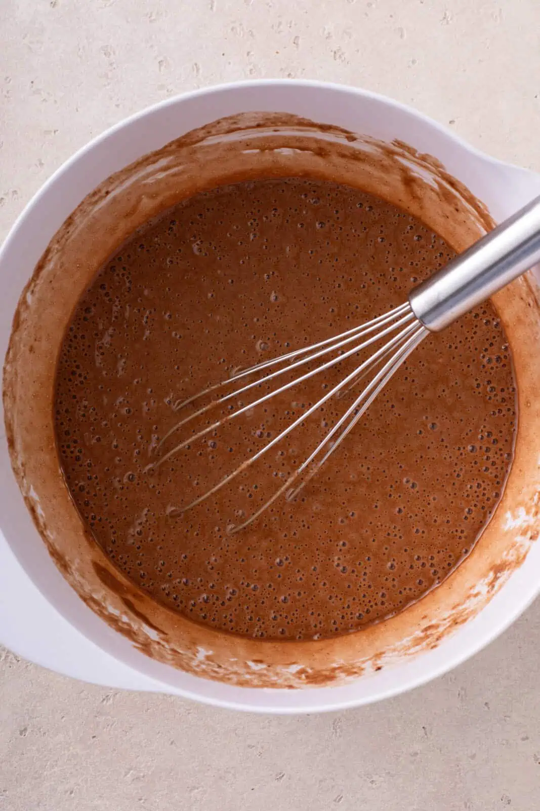Cake batter for easy chocolate cupcakes whisked in a white mixing bowl.