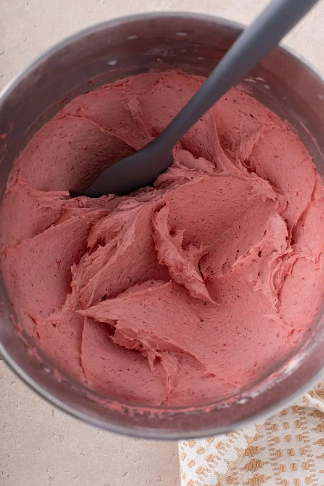 Strawberry buttercream frosting mixed in the bowl of a stand mixer.