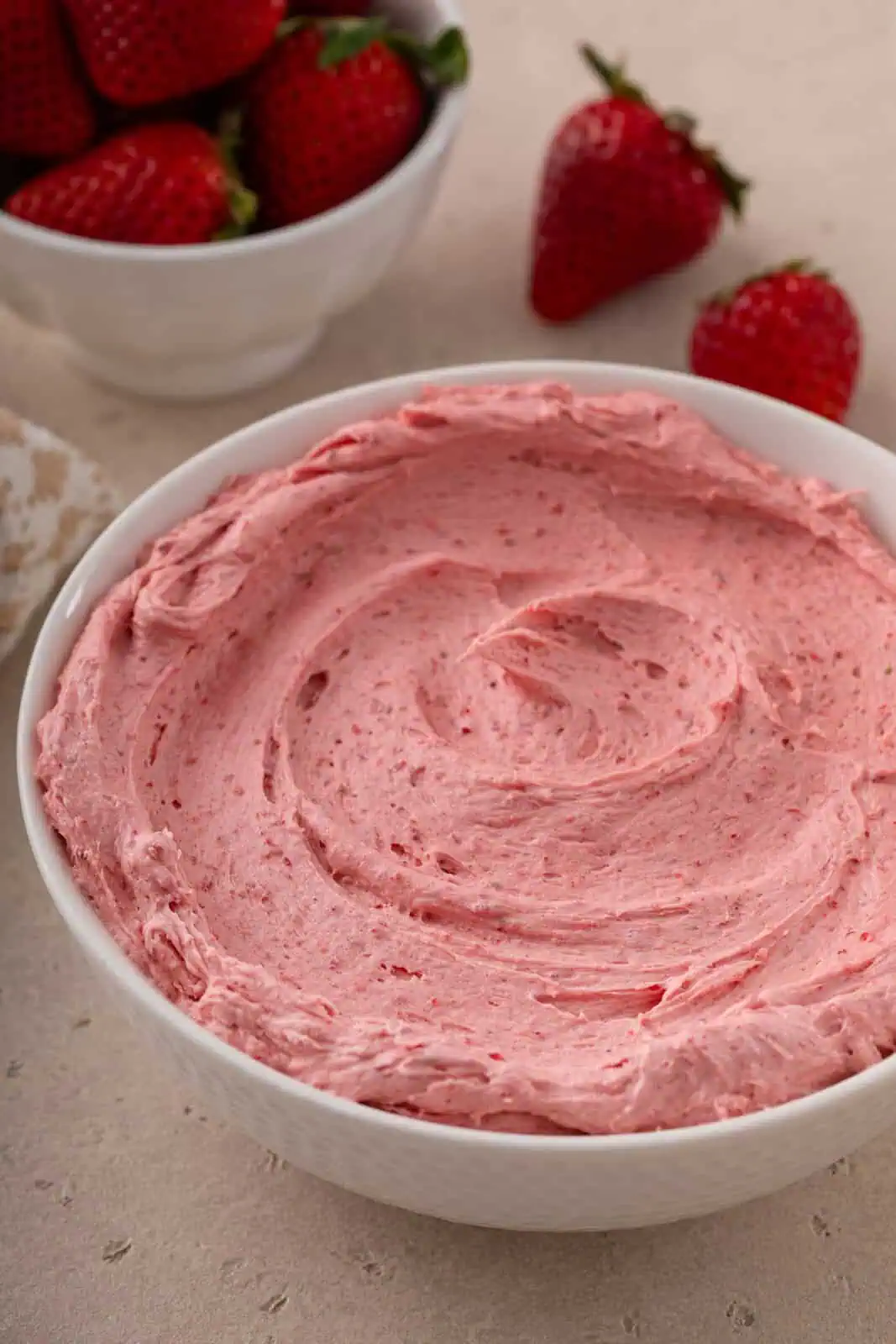 Pink strawberry buttercream frosting in a white bowl.