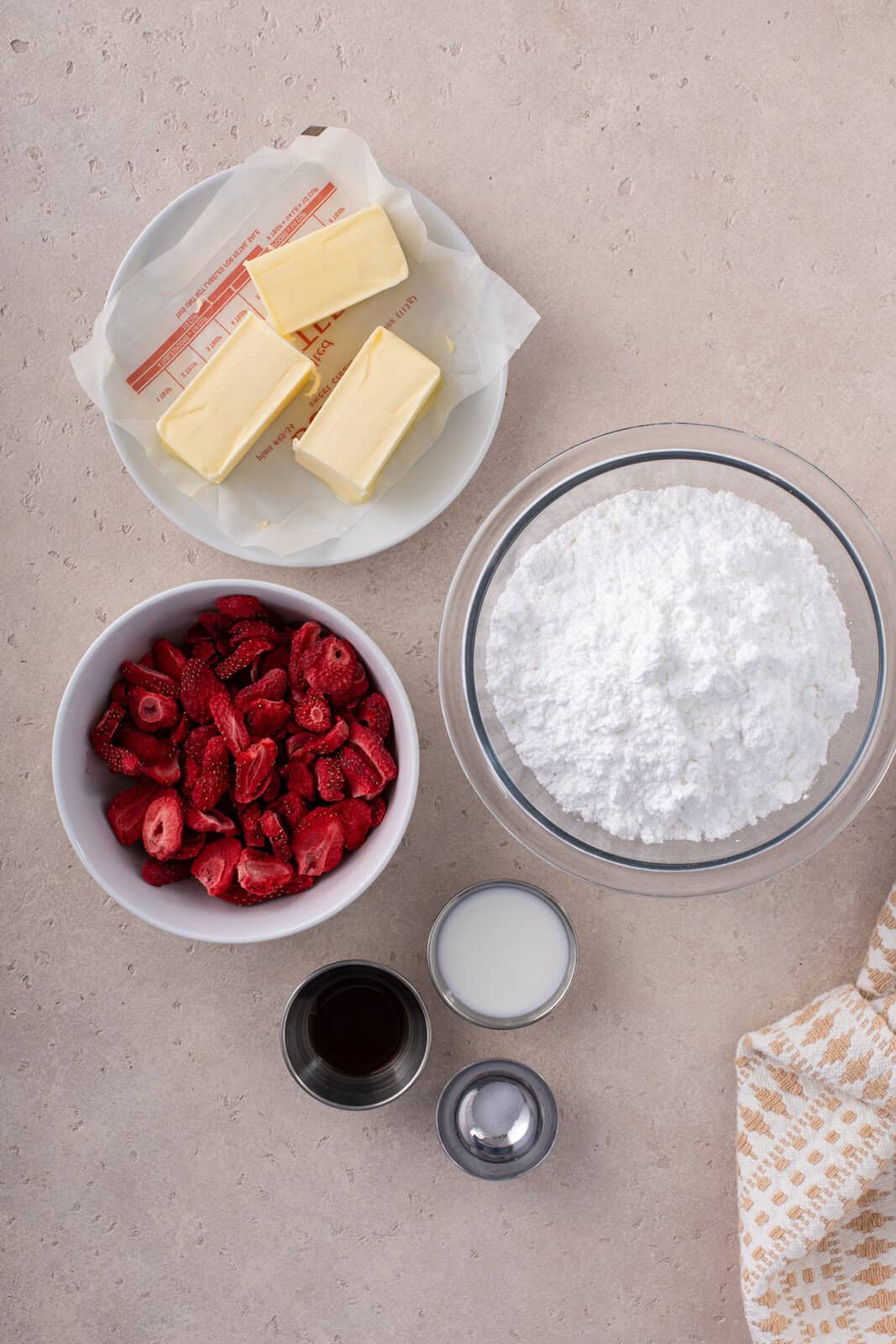 Ingredients for strawberry buttercream frosting arranged on a countertop.