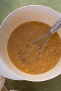 Wet ingredients for bisquick banana bread whisked in a white bowl.