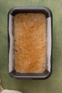 Unbaked bisquick banana bread in a parchment-lined loaf pan, ready to go in the oven.