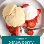 Overhead view of strawberry shortcake on a white plate, with a fork taking a bite of the cake, strawberries, and whipped cream. Text overlay includes recipe name.