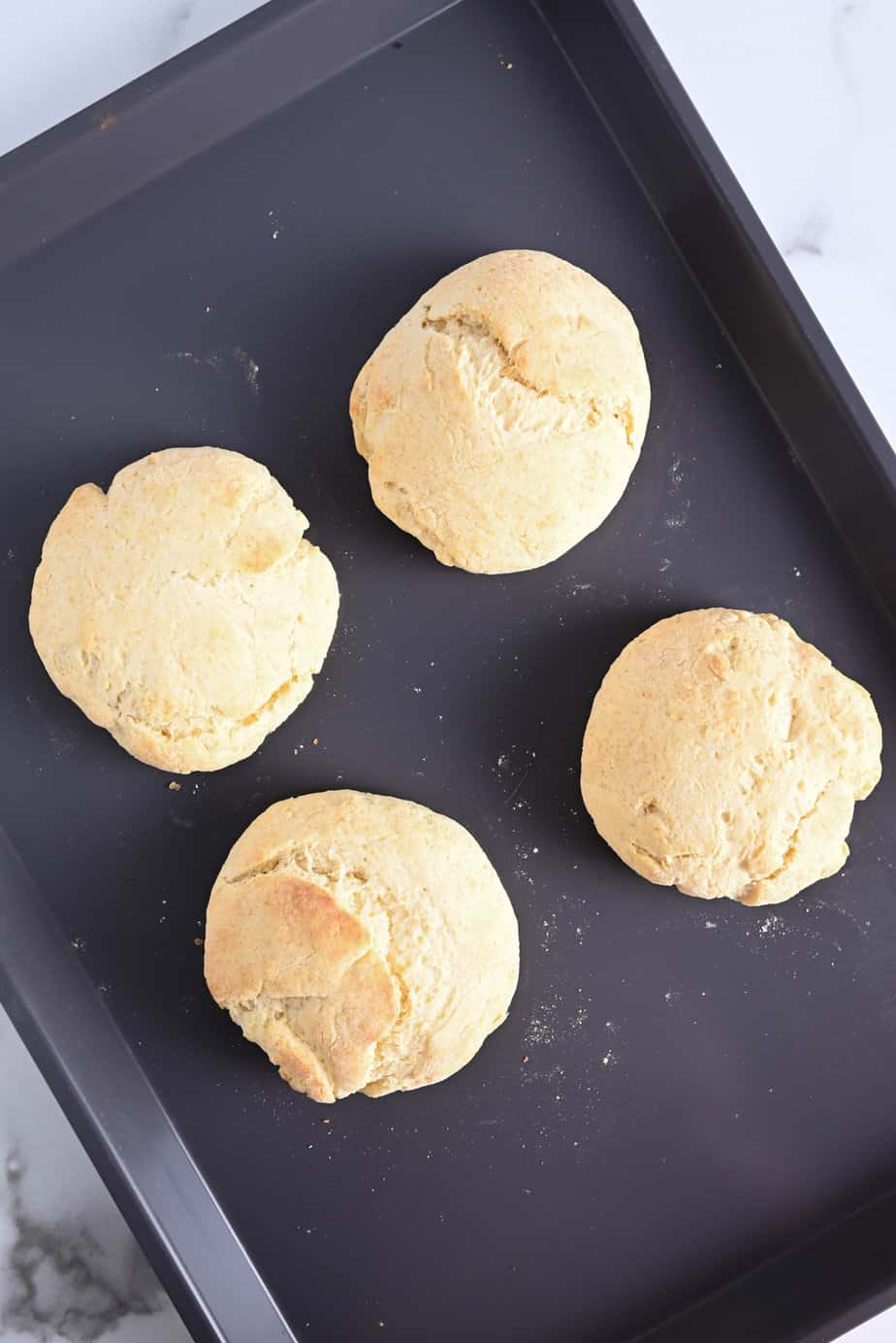 Four baked shortcakes on a baking sheet.