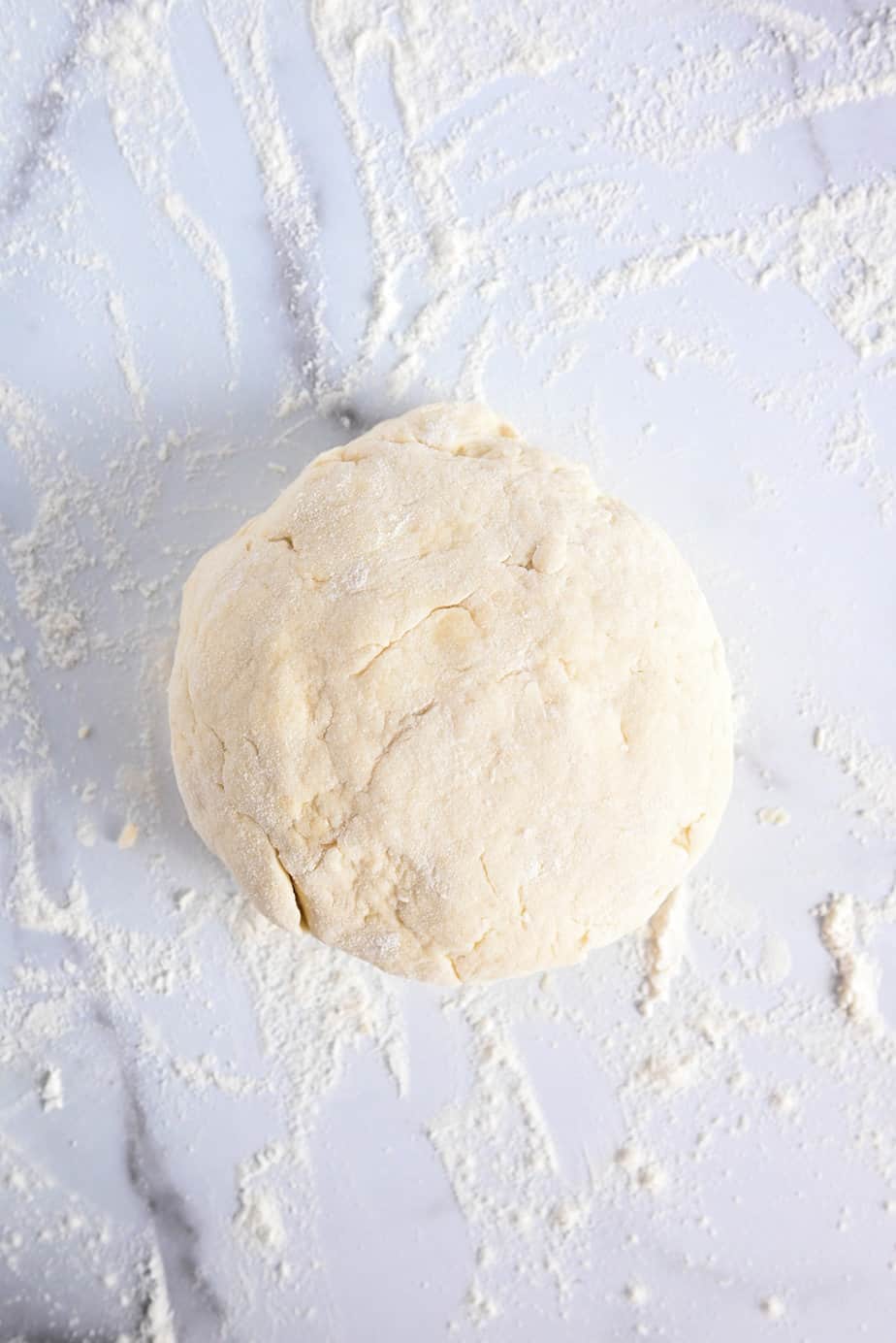 Kneaded dough for strawberry shortcake on a lightly floured marble countertop.