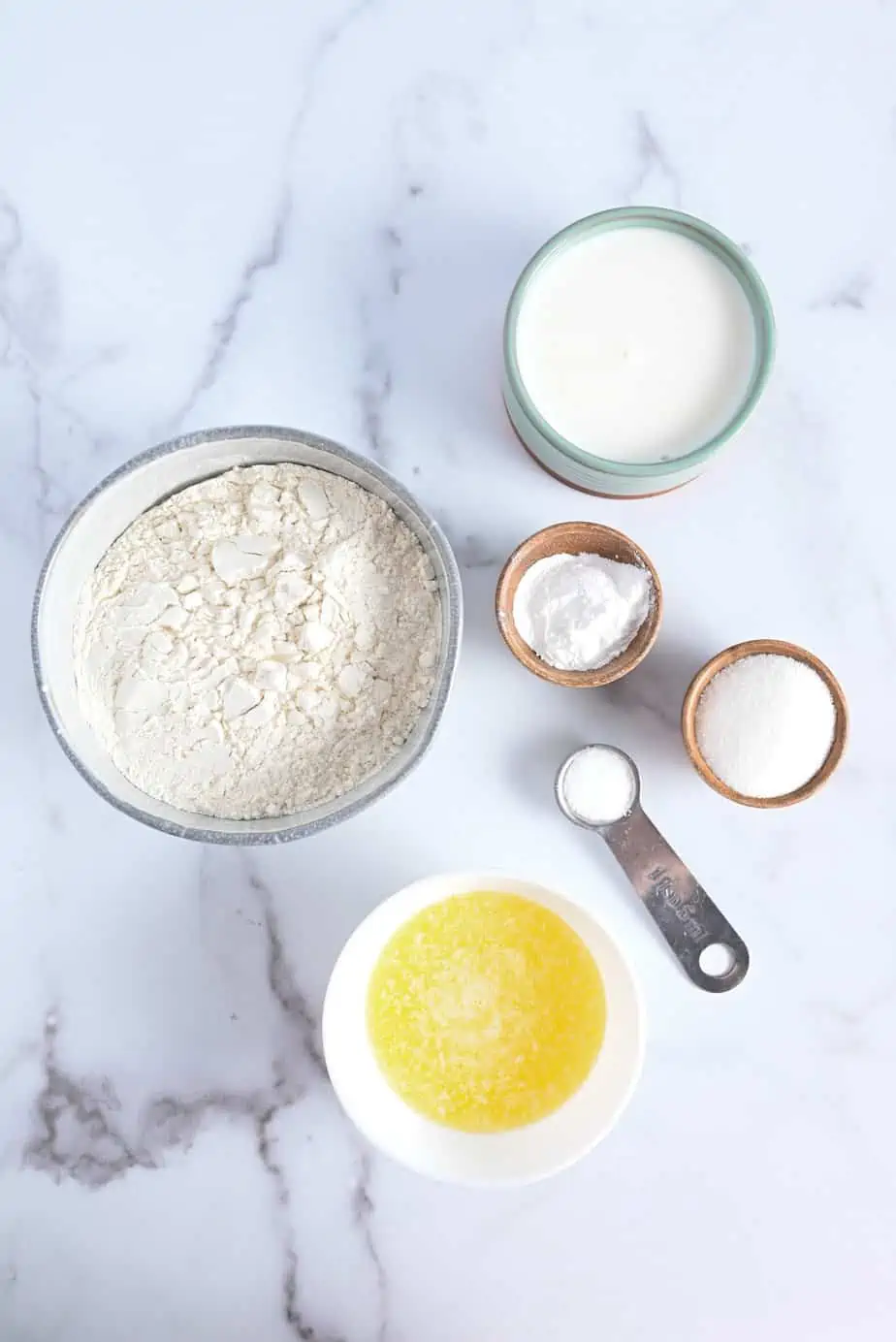 Ingredients for strawberry shortcake arranged on a marble countertop.