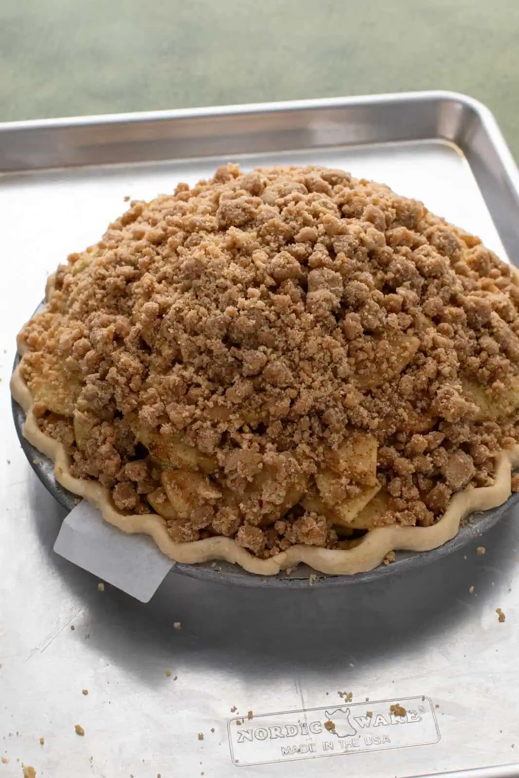 Crumb topping pressed onto the outside of a dutch apple pie, ready to go in the oven.