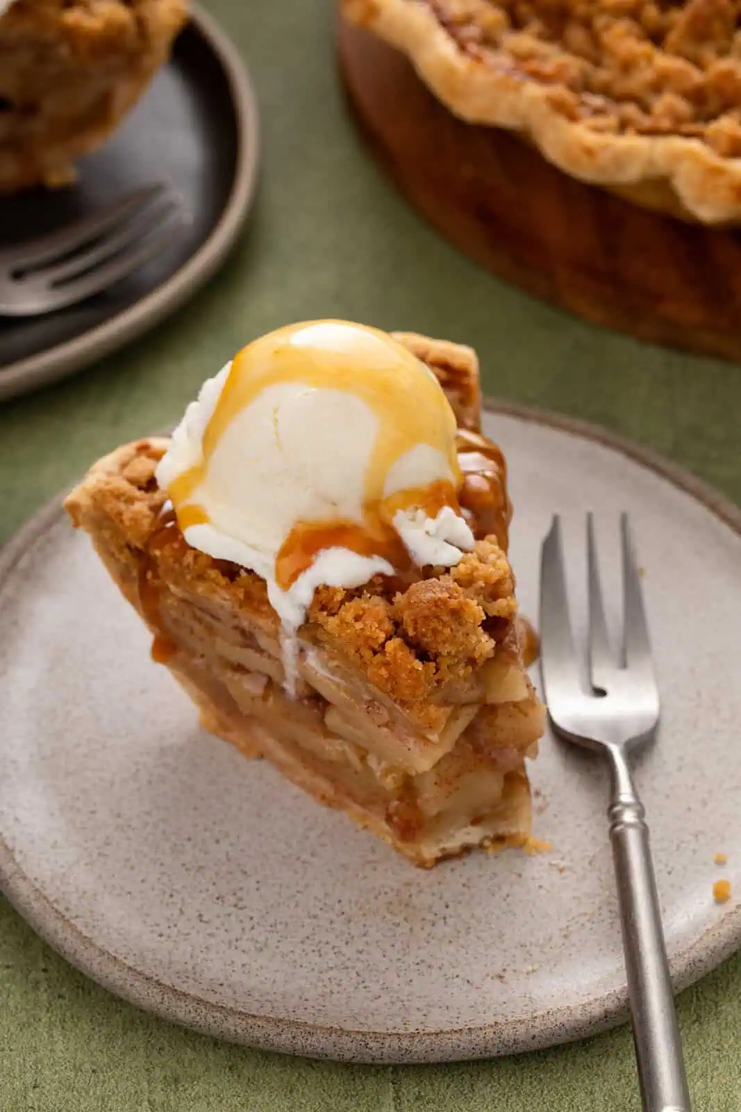 Caramel sauce drizzled over dutch apple pie a la mode. A bite has been taken from the pie.