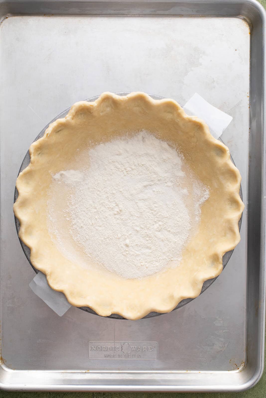 Granulated sugar and flour mixture sprinkled over the bottom of a pie crust in a deep-dish pie plate.