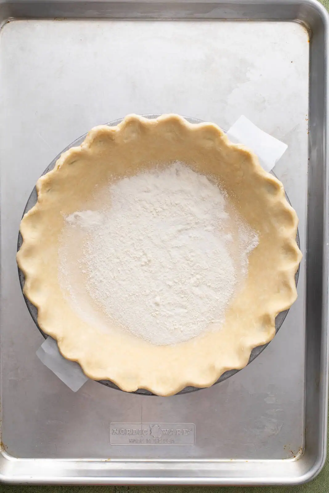 Granulated sugar and flour mixture sprinkled over the bottom of a pie crust in a deep-dish pie plate.