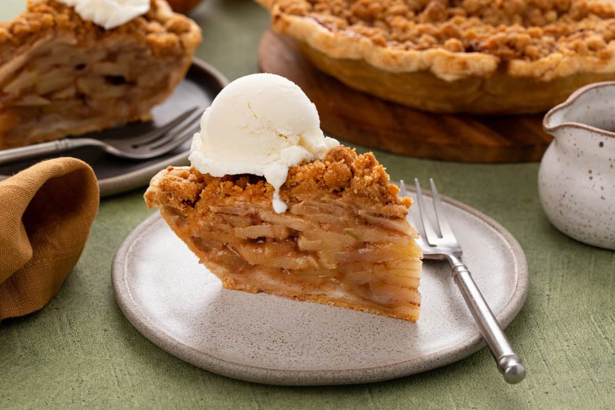 Slice of dutch apple pie a la mode on a white plate.