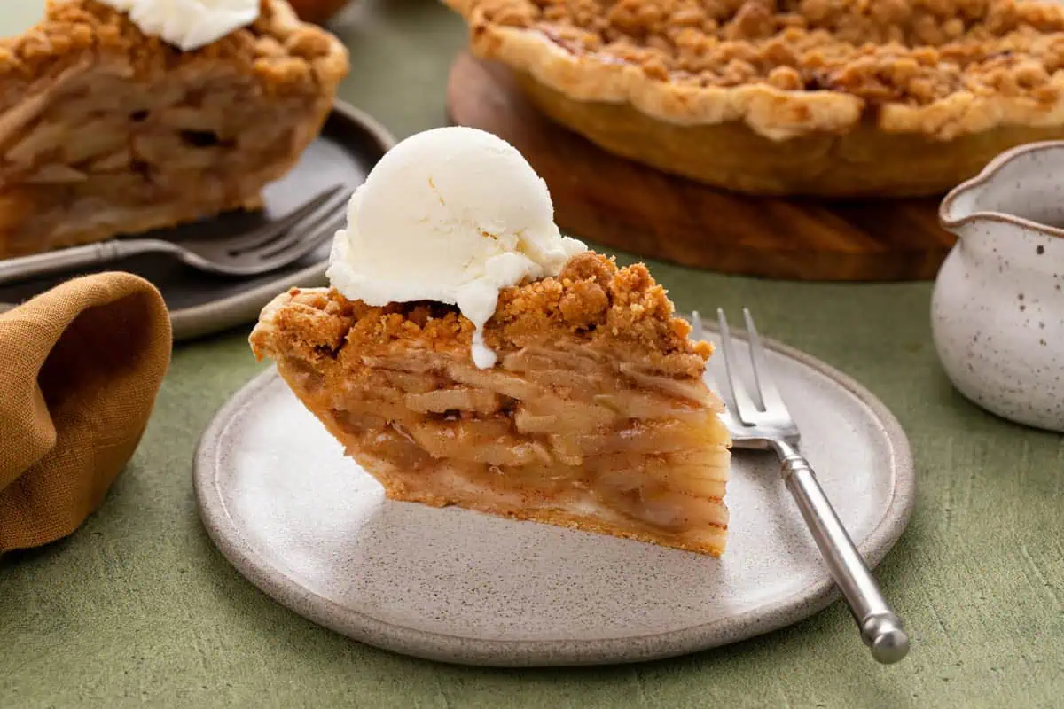 Slice of dutch apple pie a la mode on a white plate.