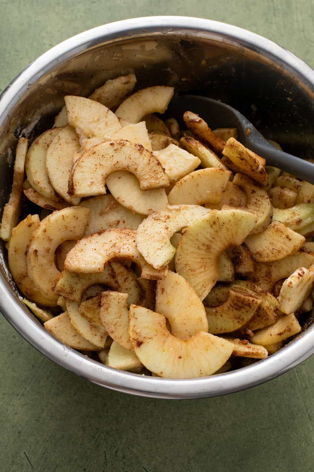 Filling for dutch apple pie stirred together in a large metal mixing bowl.