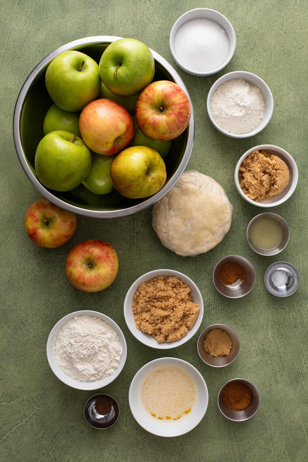 Ingredients for dutch apple pie arranged on a green countertop.