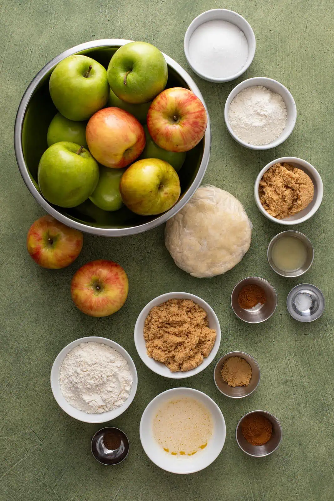 Ingredients for dutch apple pie arranged on a green countertop.