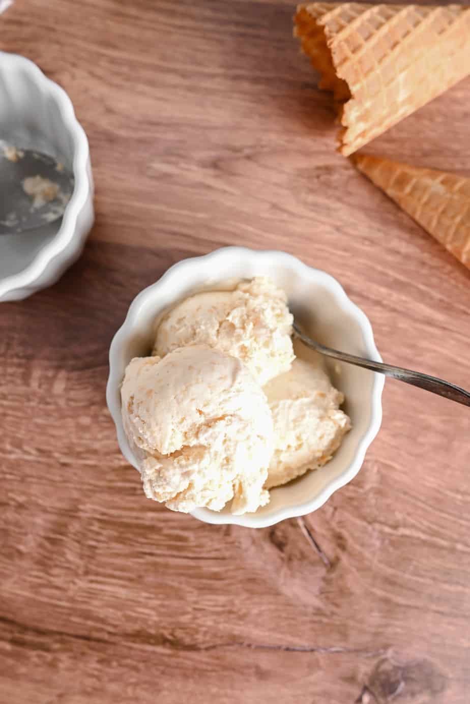 White bowl filled with peach ice cream set on a wooden countertop.