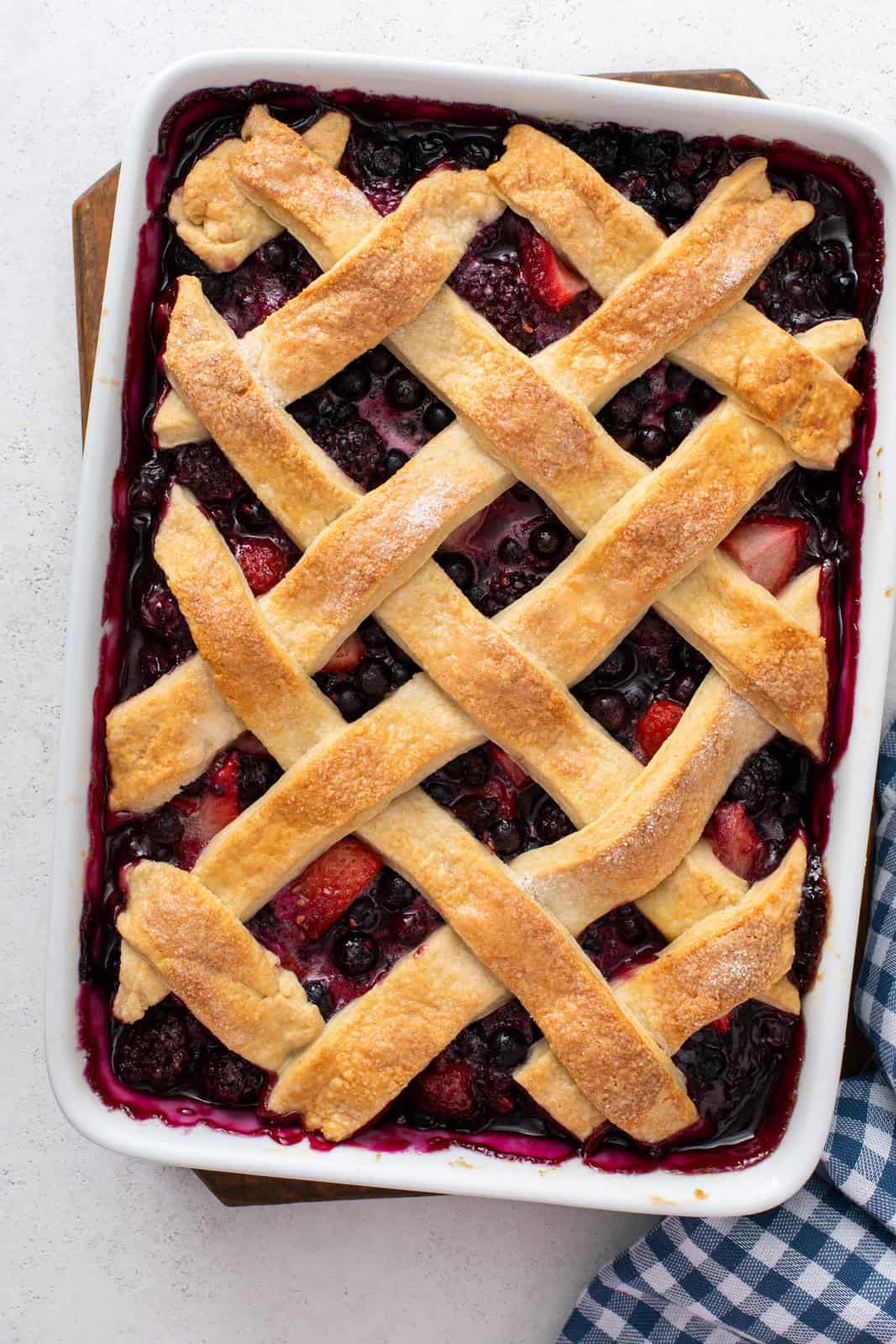 Baked mixed berry cobbler in a white baking dish.